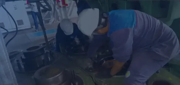 Profissional com máscara de proteção trabalhando em um componente metálico na oficina